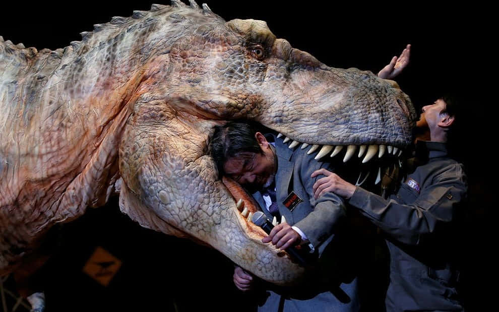 En mand holder en t-rex foran en scene