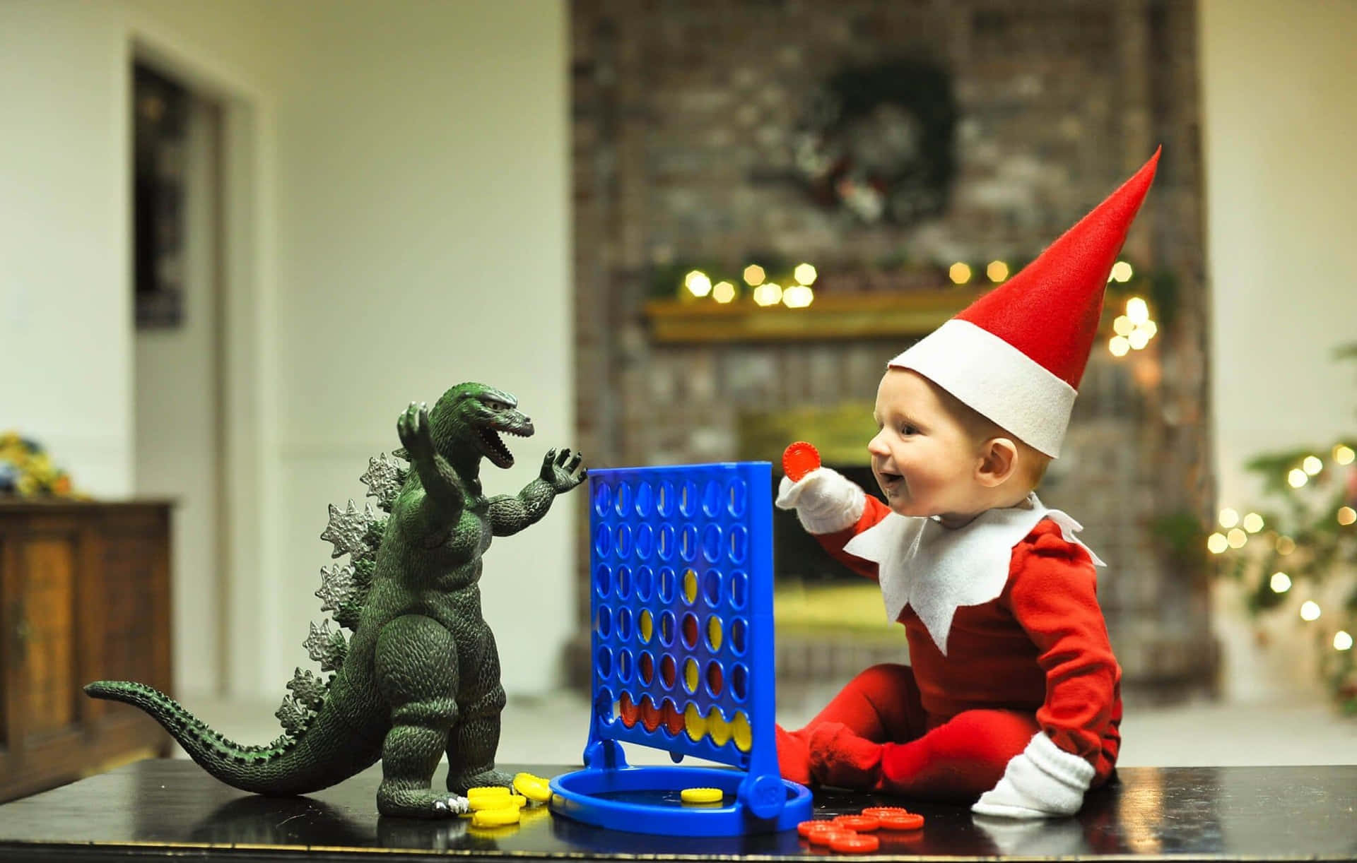 A Baby Dressed As An Elf Plays With A Toy Godzilla