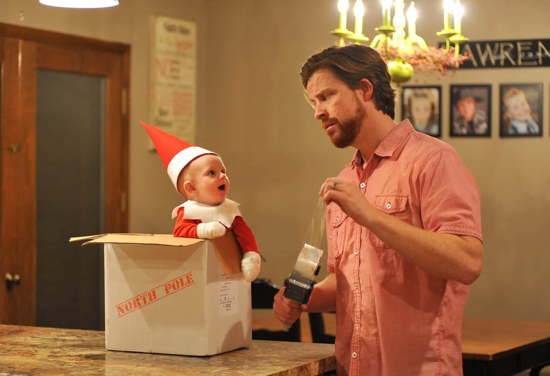 A Man Dressed As An Elf Is Holding A Baby In A Box