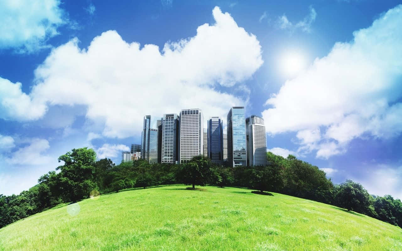 A Green Grassy Field With Buildings And Clouds