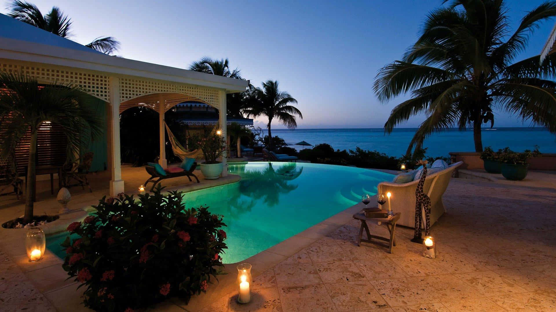 A Pool With Candles And Chairs At Night