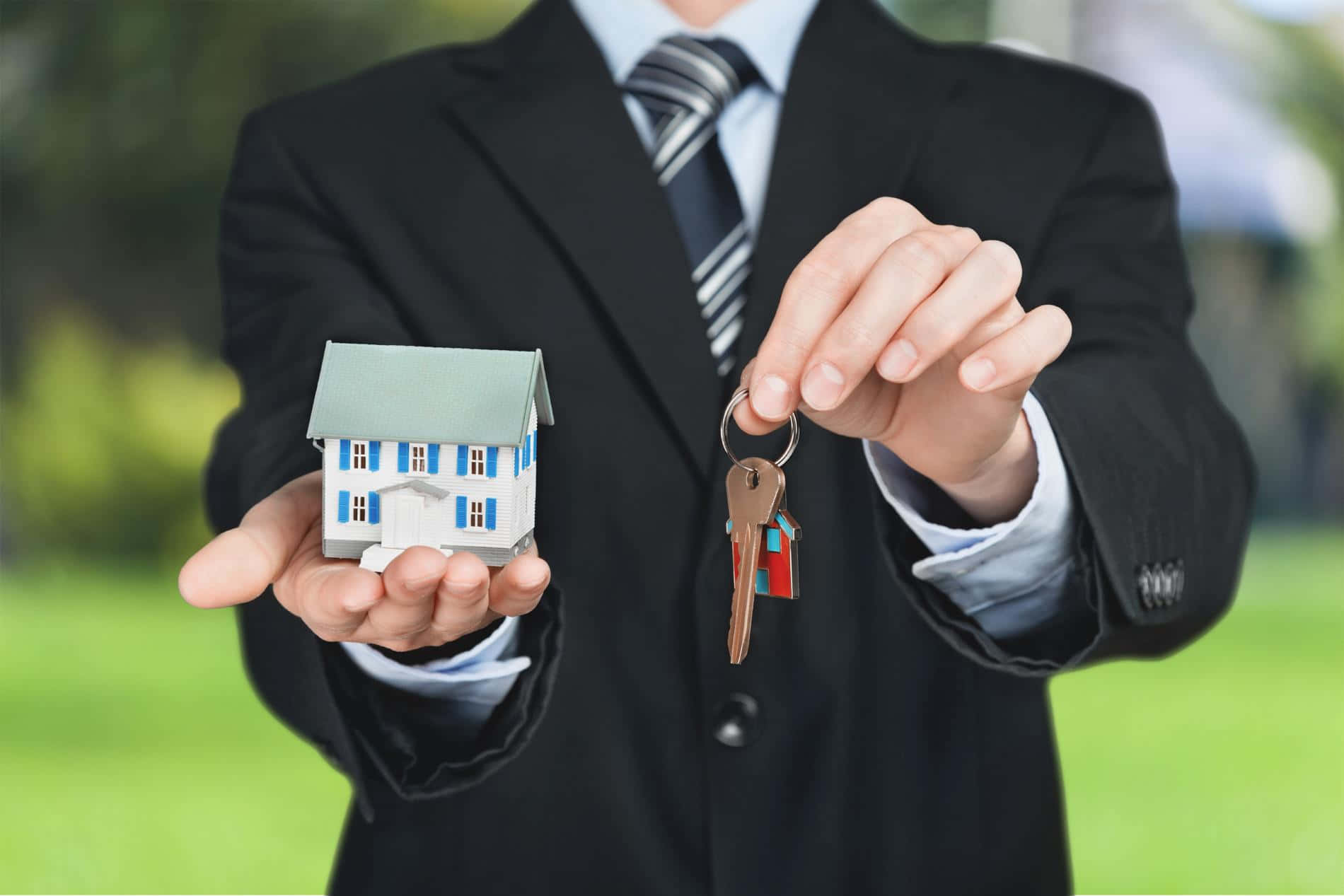 A Man Holding A House Model And Keys