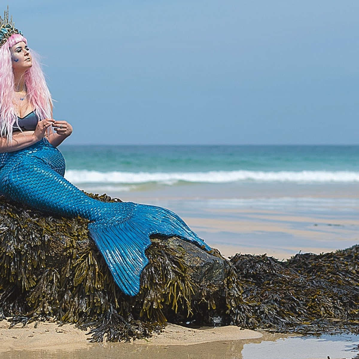 Жена в костюм на русалка, седнала на плажен тапет