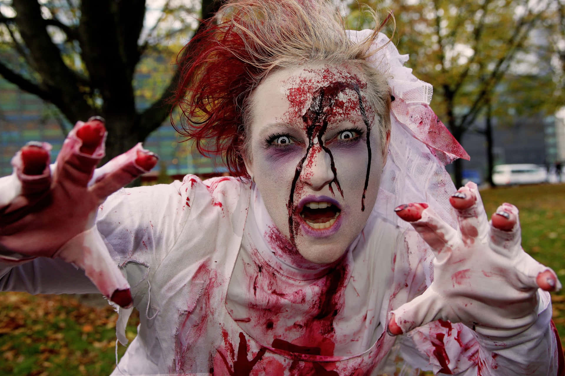 a woman dressed in a zombie costume is holding her hands
