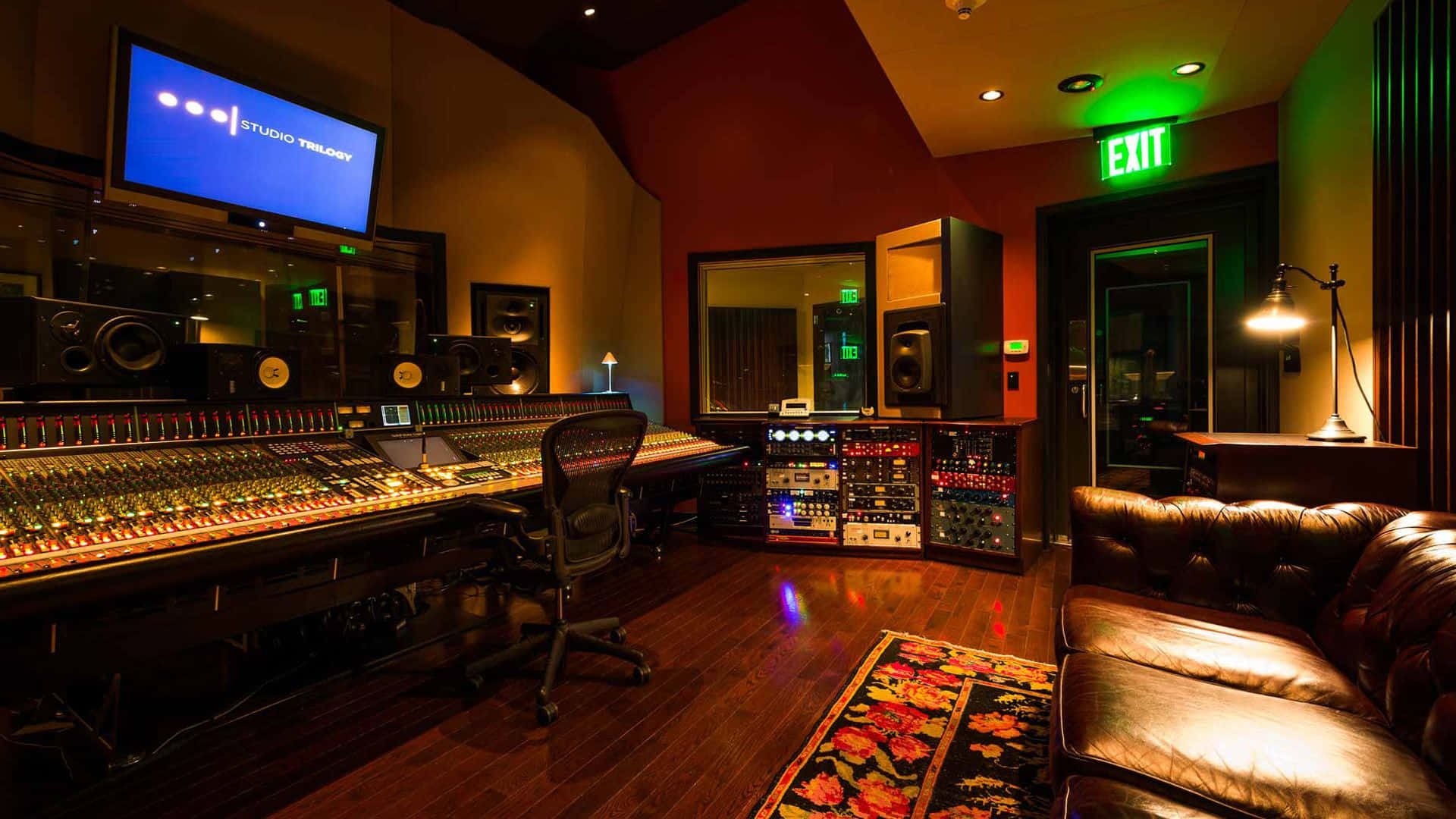 A Recording Studio With A Large Monitor And A Leather Couch