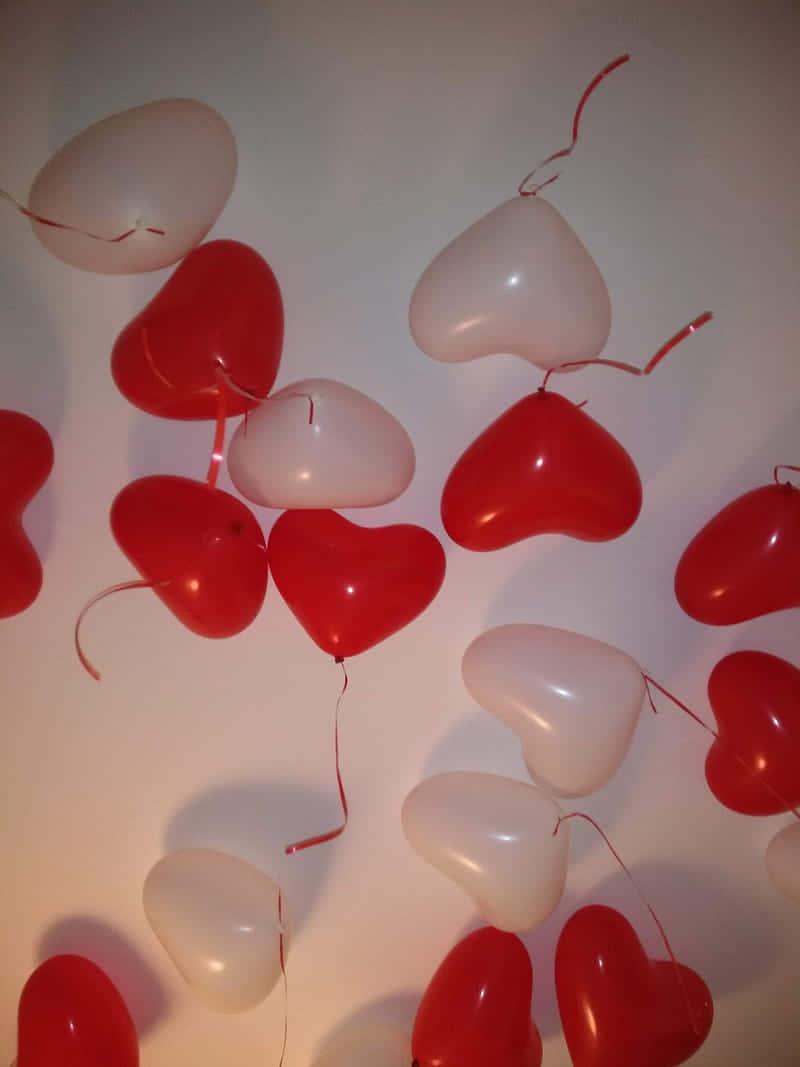 A Group Of Red And White Balloons Hanging From A Ceiling Wallpaper