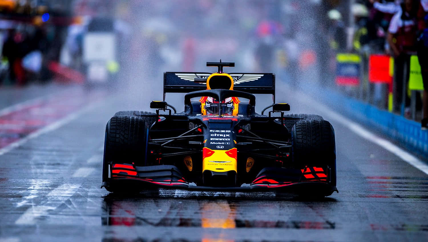 a red bull racing car driving down a track in the rain