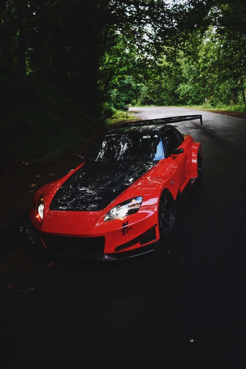 A Red Sports Car Is Parked In The Woods Wallpaper