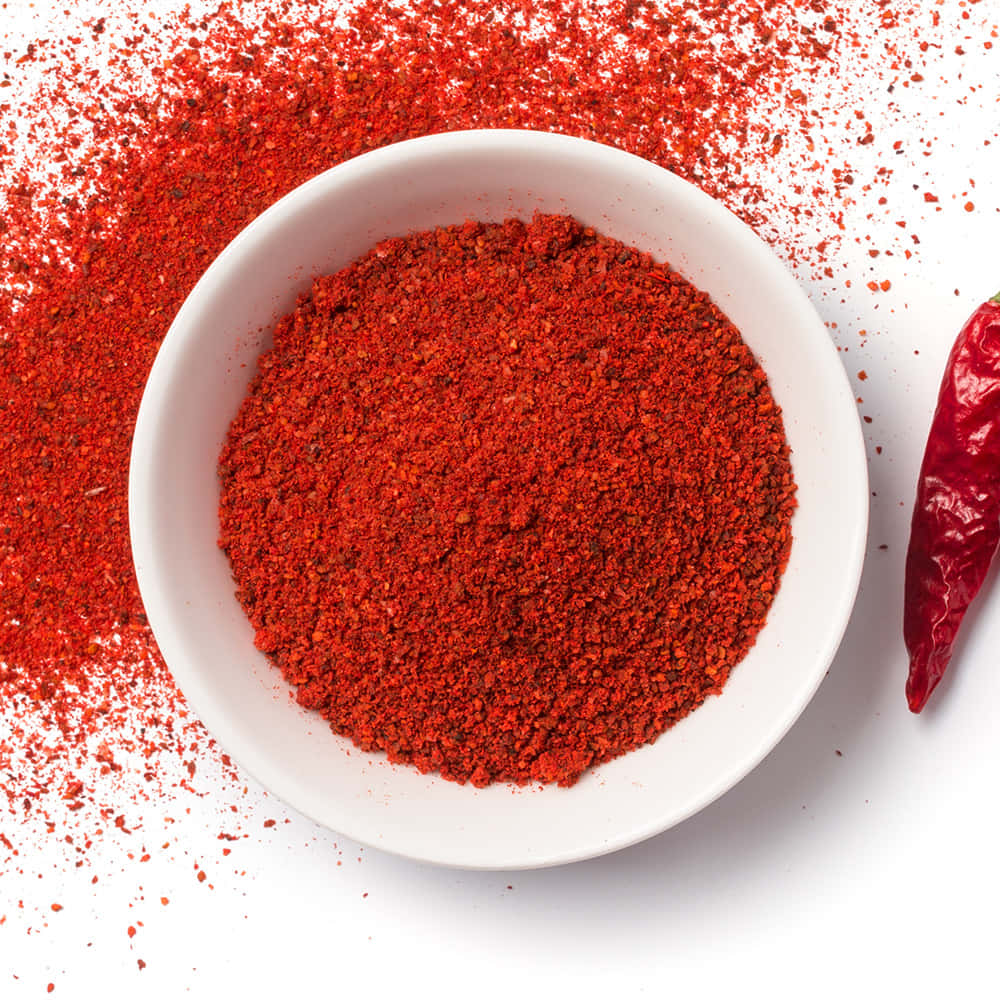 Vibrant Ground Red Chili Powder Spilled from a Ceramic Bowl Wallpaper