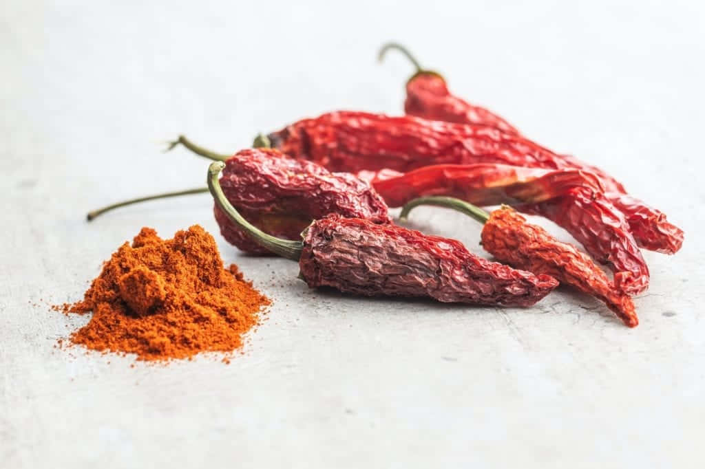 Fiery Red Chili Powder in a Rustic Bowl Wallpaper