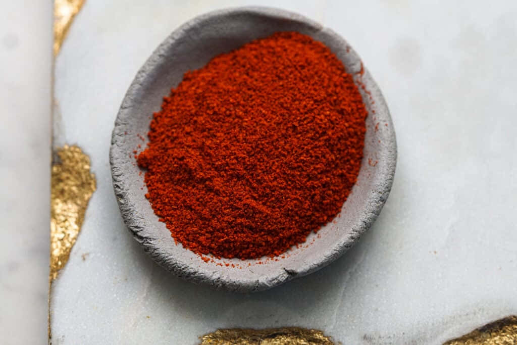 Vibrant Red Chili Powder in a Rustic Bowl Wallpaper