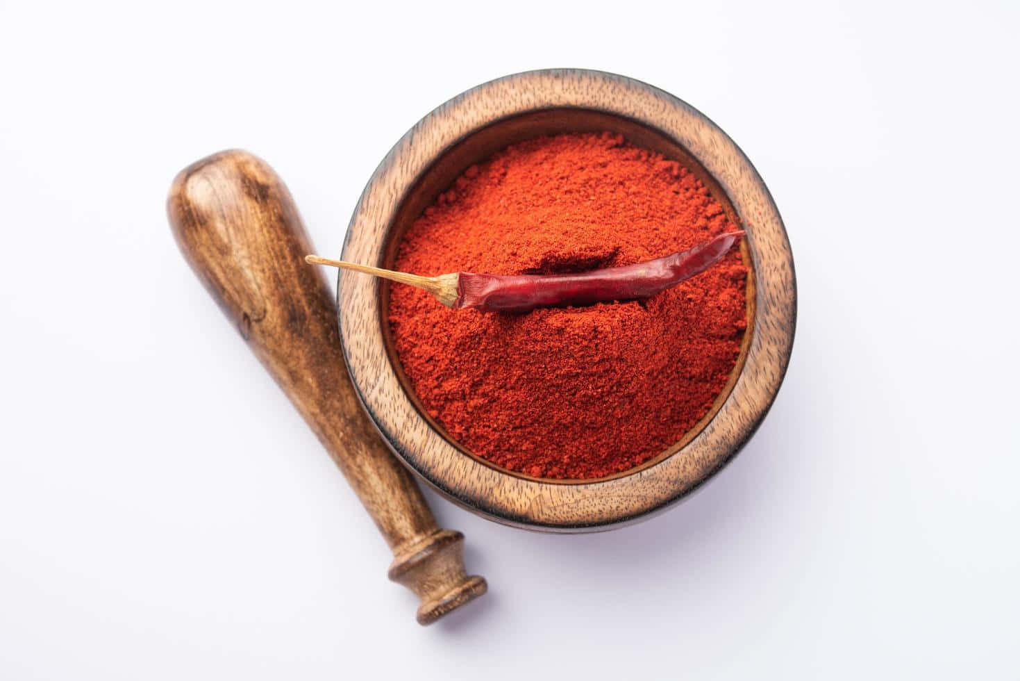 Vibrant Red Chili Powder displayed on a wooden surface Wallpaper
