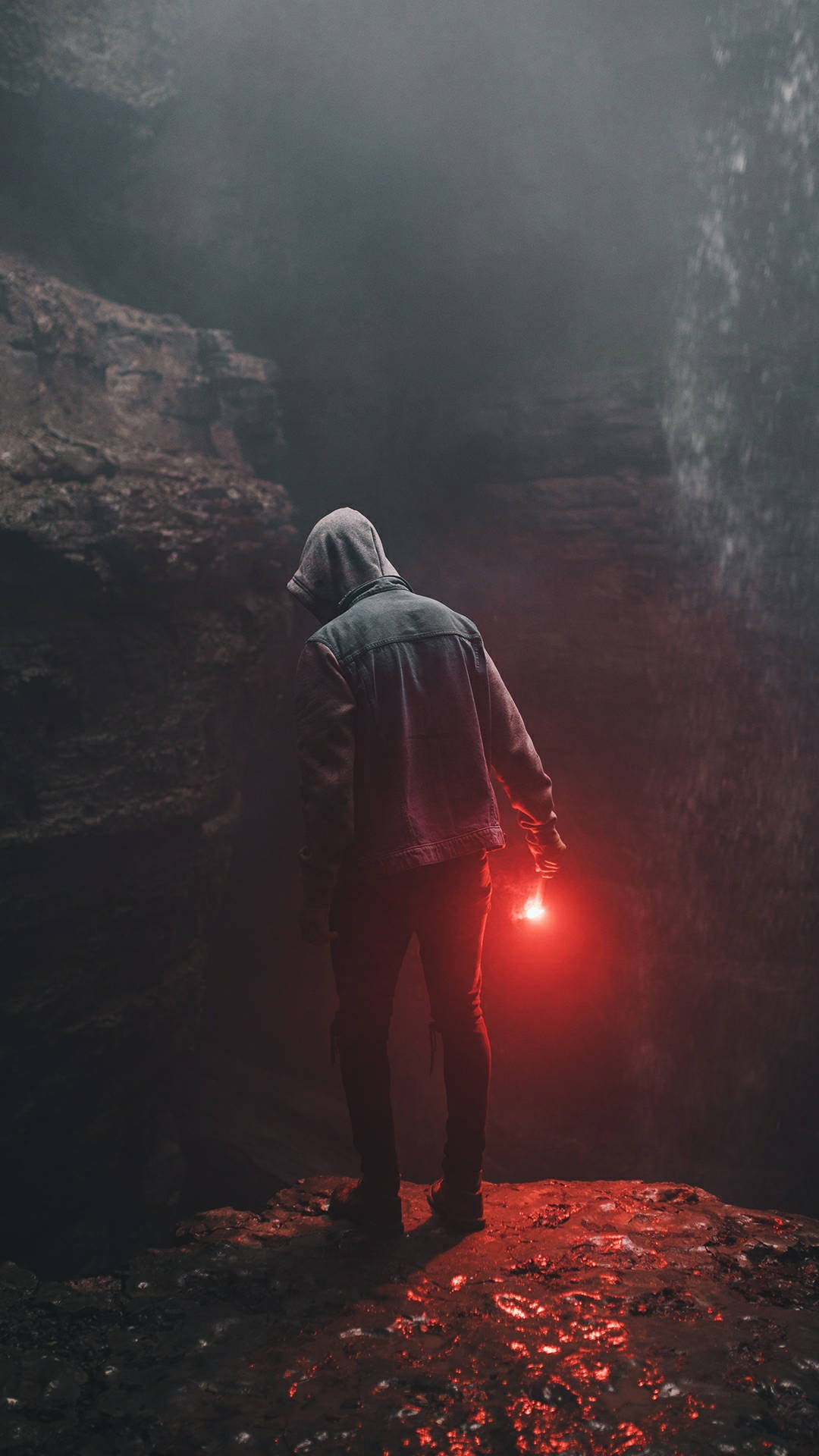 A Man Standing On A Cliff With A Flashlight Wallpaper