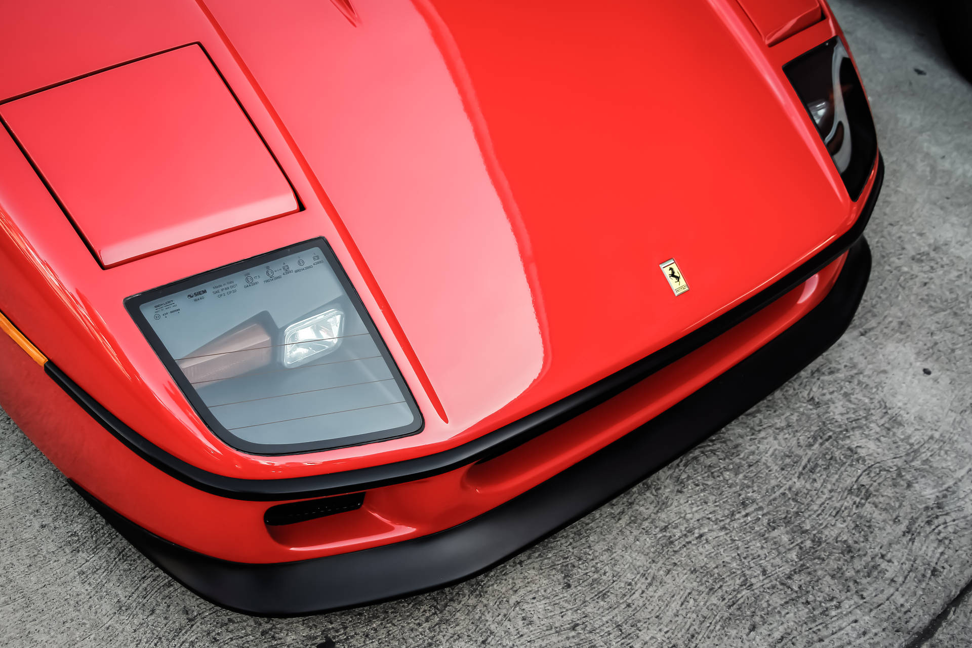 Red Ferrari sports car hood cover with logo badge wallpaper.