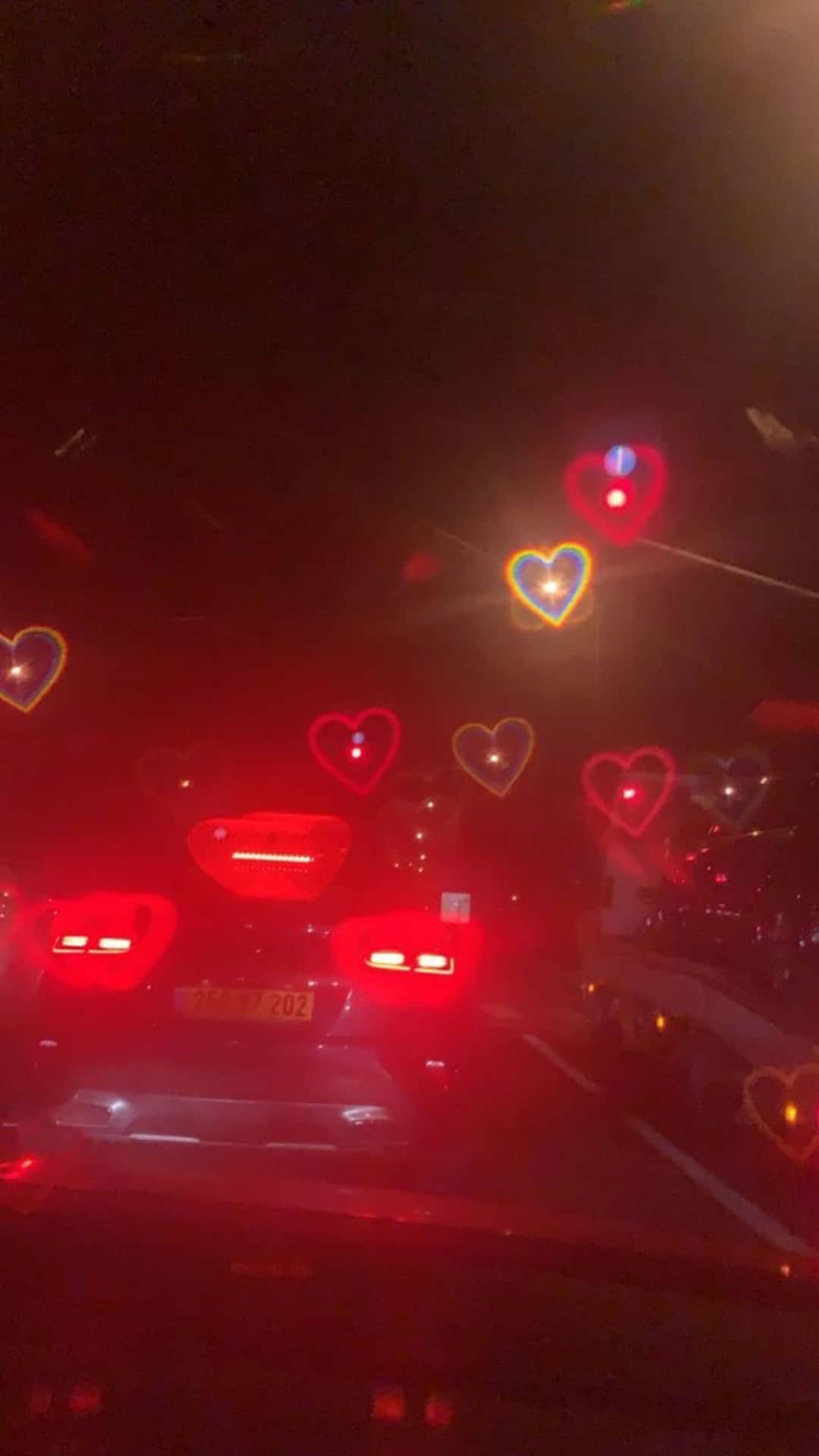 a car driving down the road at night with hearts on the windshield