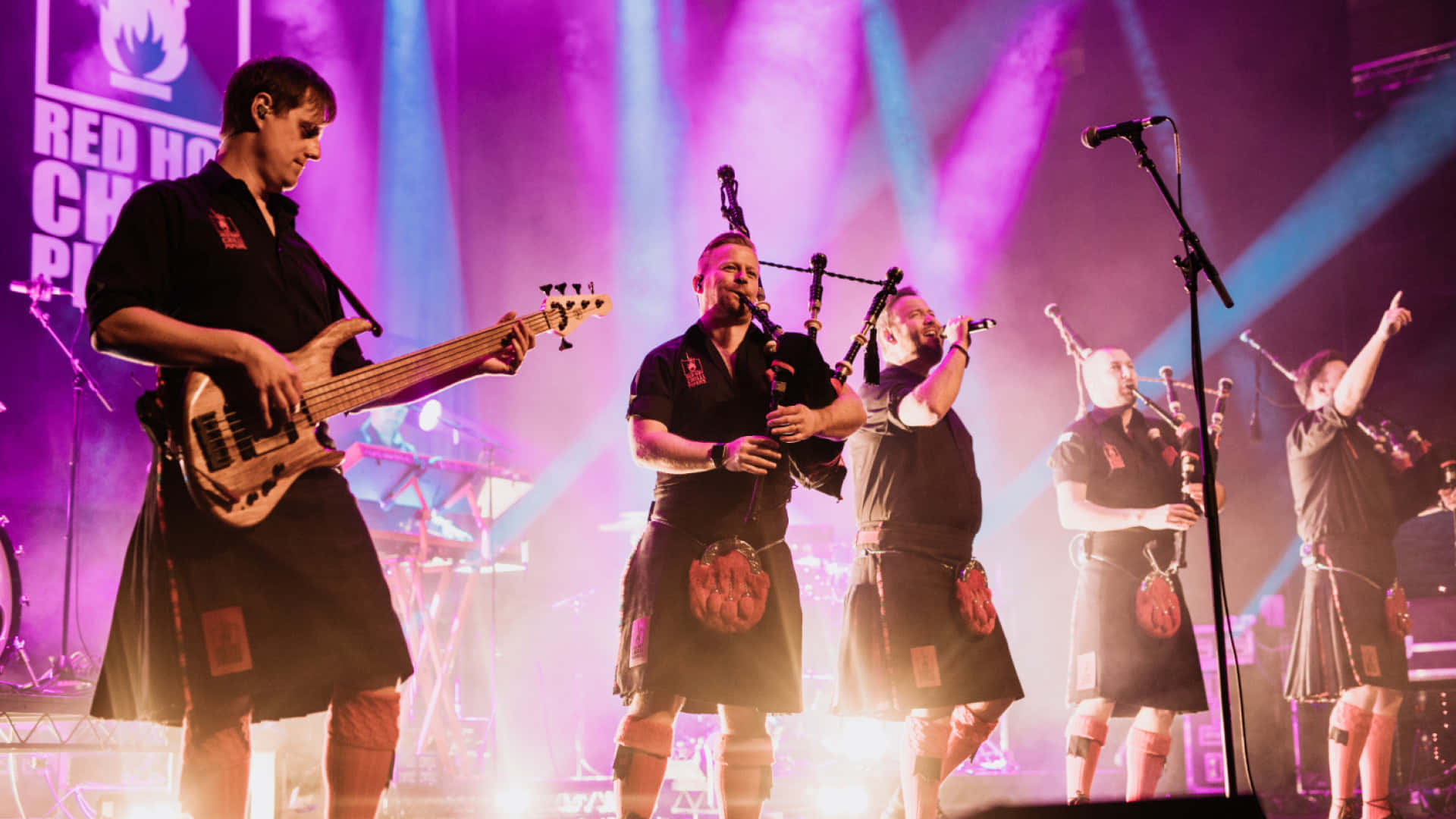 A Group Of Men In Kilts On Stage Wallpaper