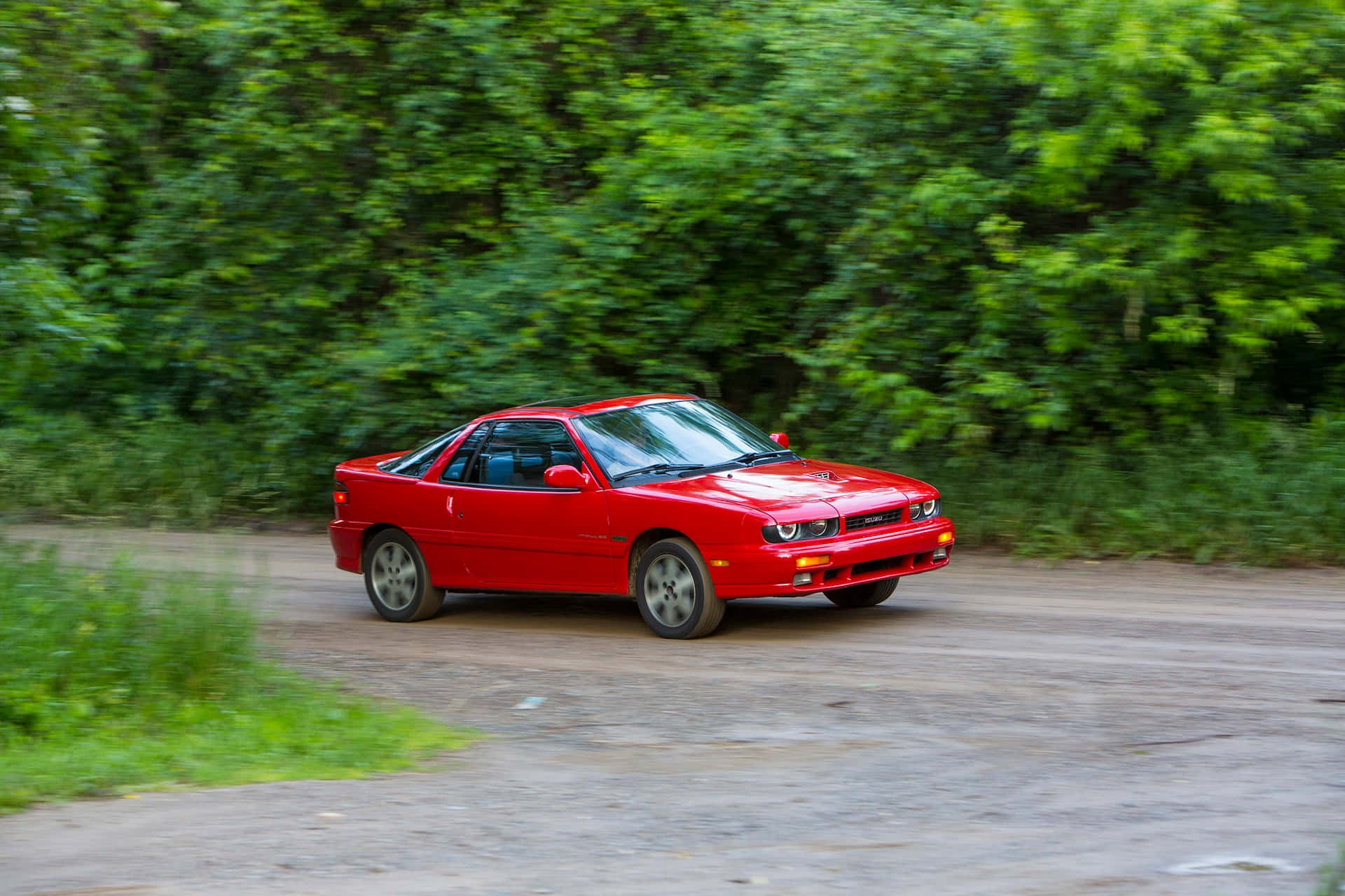 Isuzu Impulse Merah Melaju Di Jalan Tanah Wallpaper