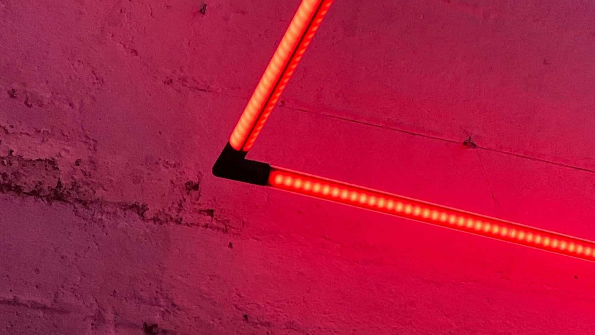 A Red Neon Light Is Hanging On A Wall Wallpaper