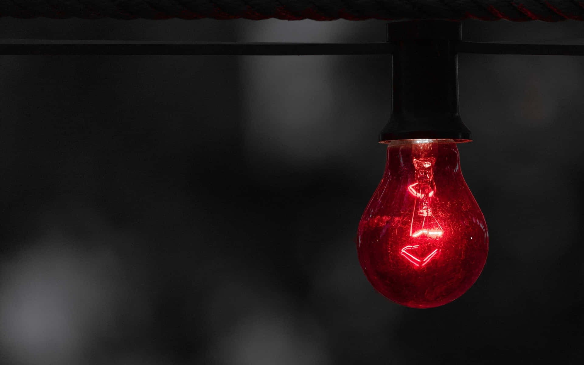 A Red Light Bulb Hanging From A Wire