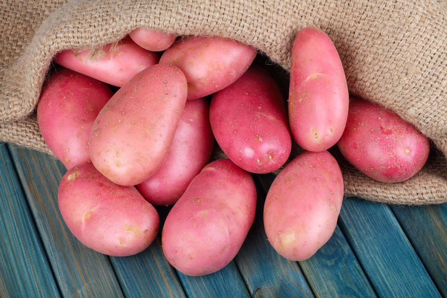 Fresh red potatoes on a rustic wooden surface Wallpaper