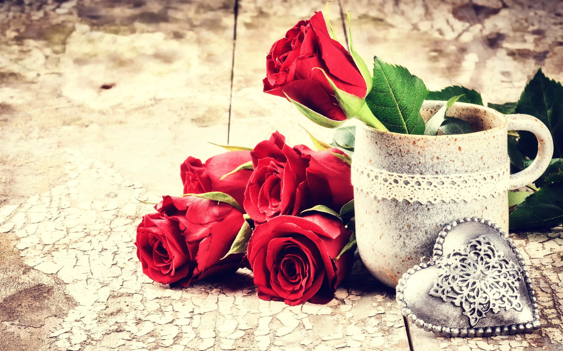 A Cup Of Red Roses And A Heart On A Wooden Table
