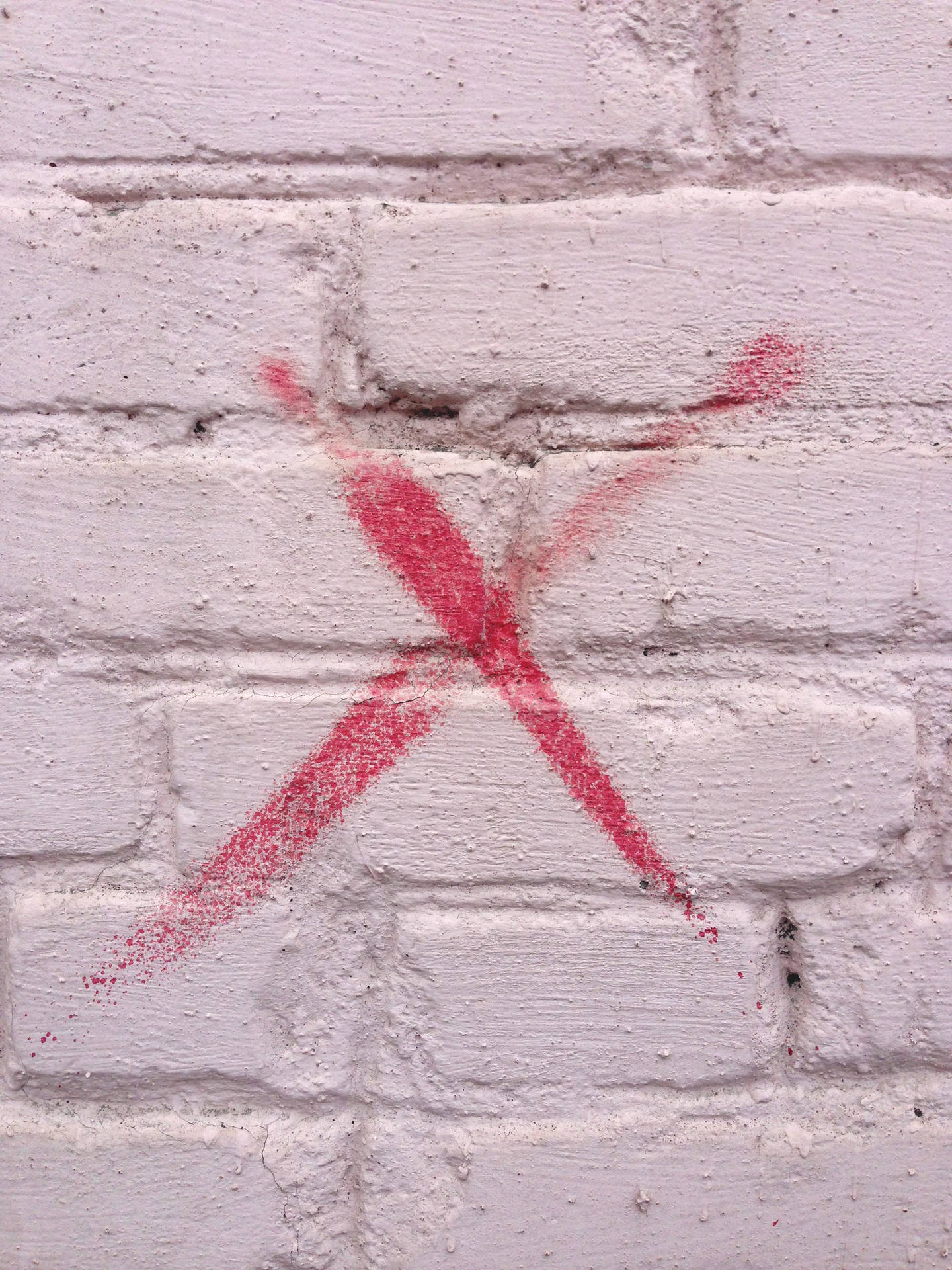 Wallpaper of red x sign as vandalized graffiti on brick wall.
