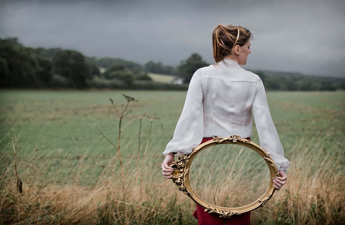 Woman Holding Mirror With Field Reflection Picture