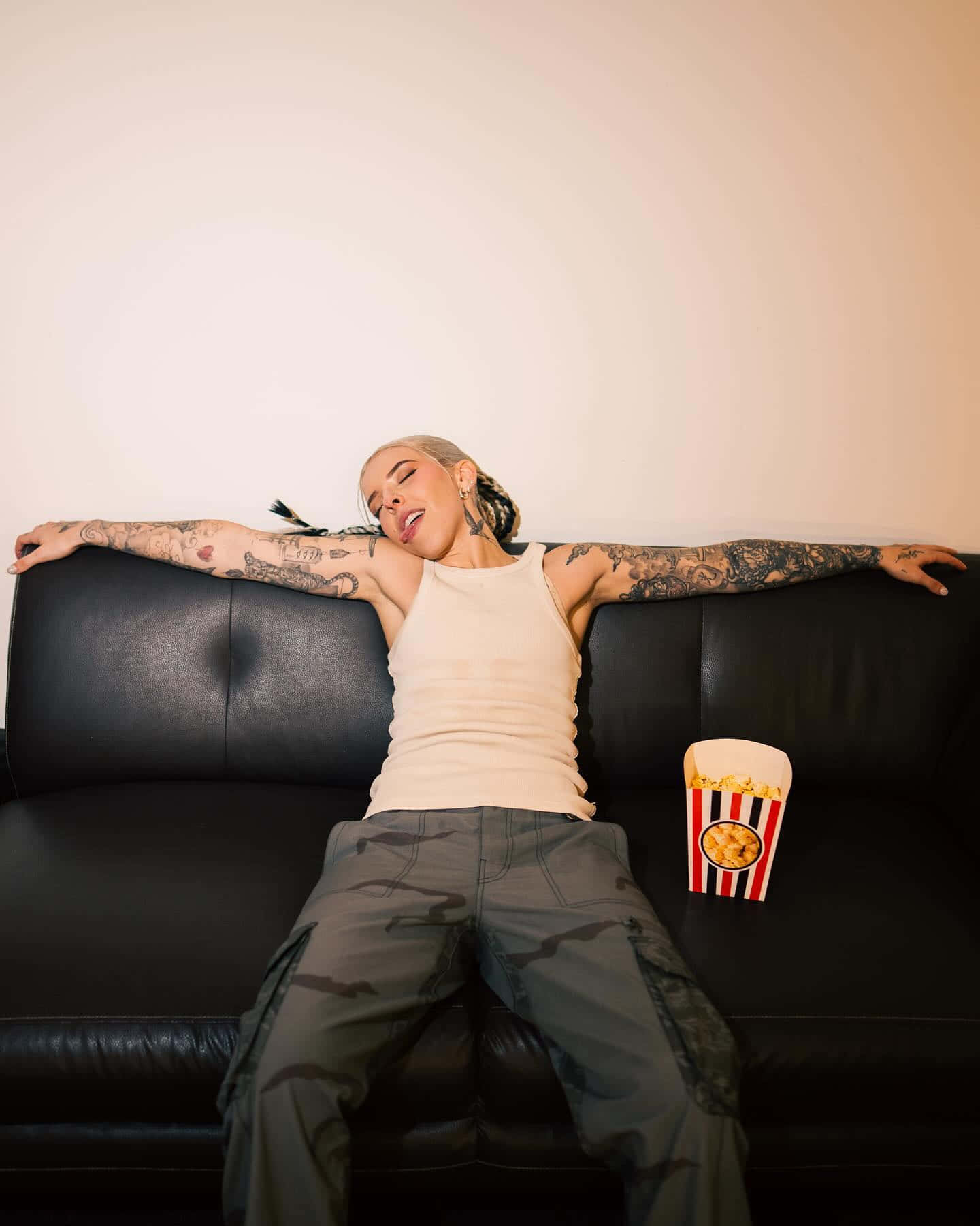 Relaxed Tattooed Womanon Sofawith Popcorn Wallpaper
