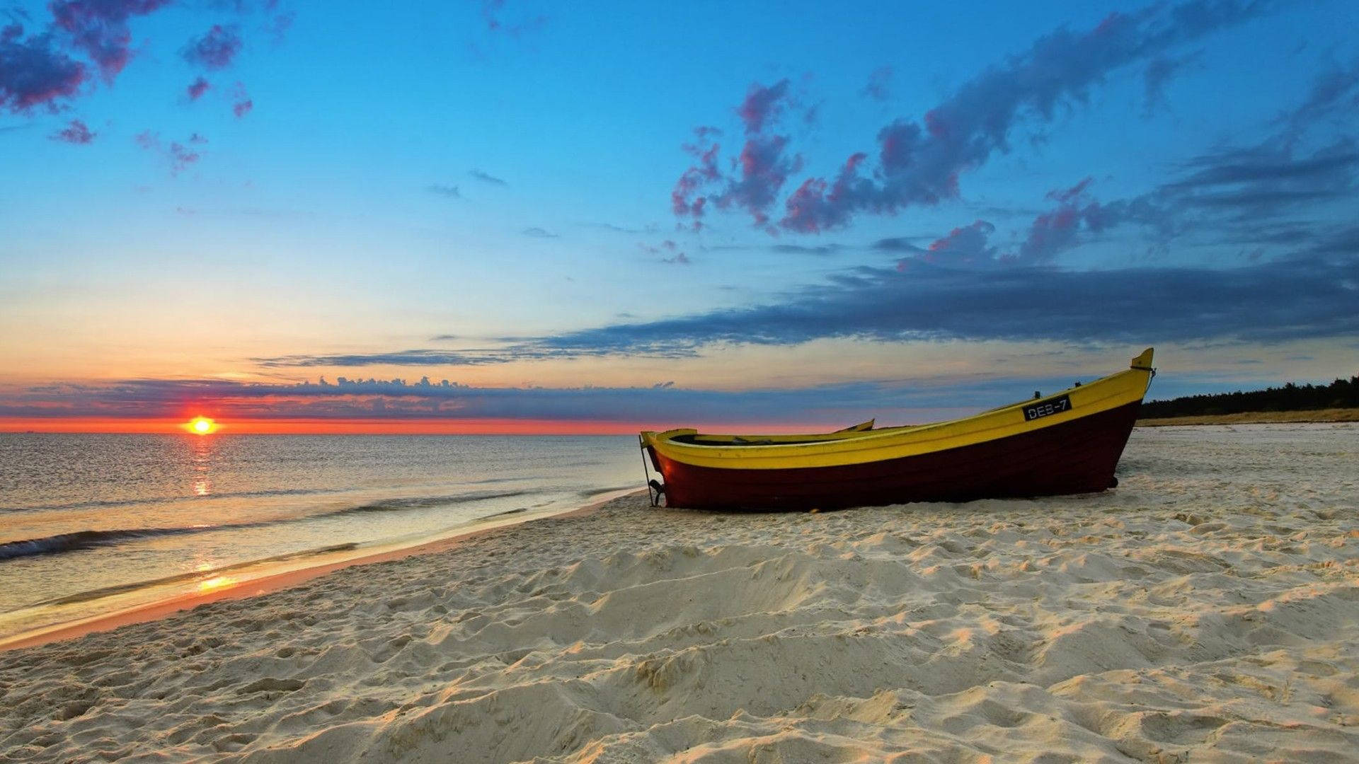 En båd på stranden ved solnedgang Wallpaper