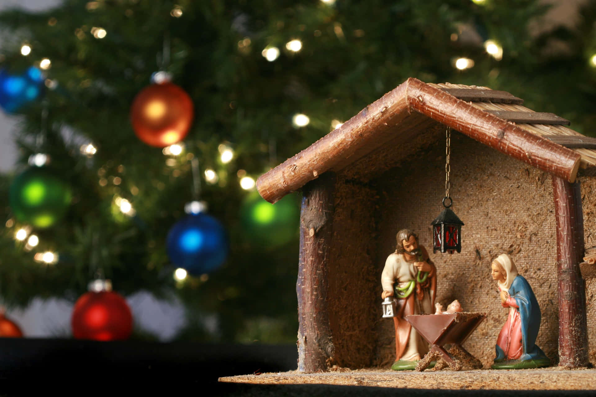 A Nativity Scene With A Christmas Tree In The Background
