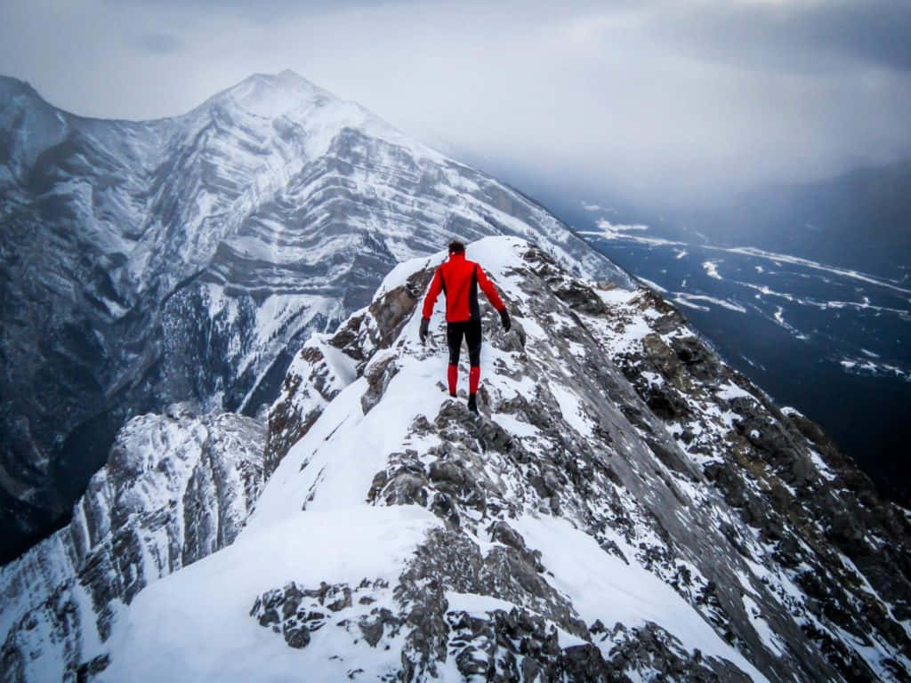 Resilient Man In Red Climbing A Mountain Alone Wallpaper