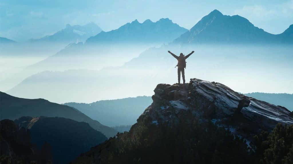 Resilient Person Conquering A Tall Mountain Wallpaper