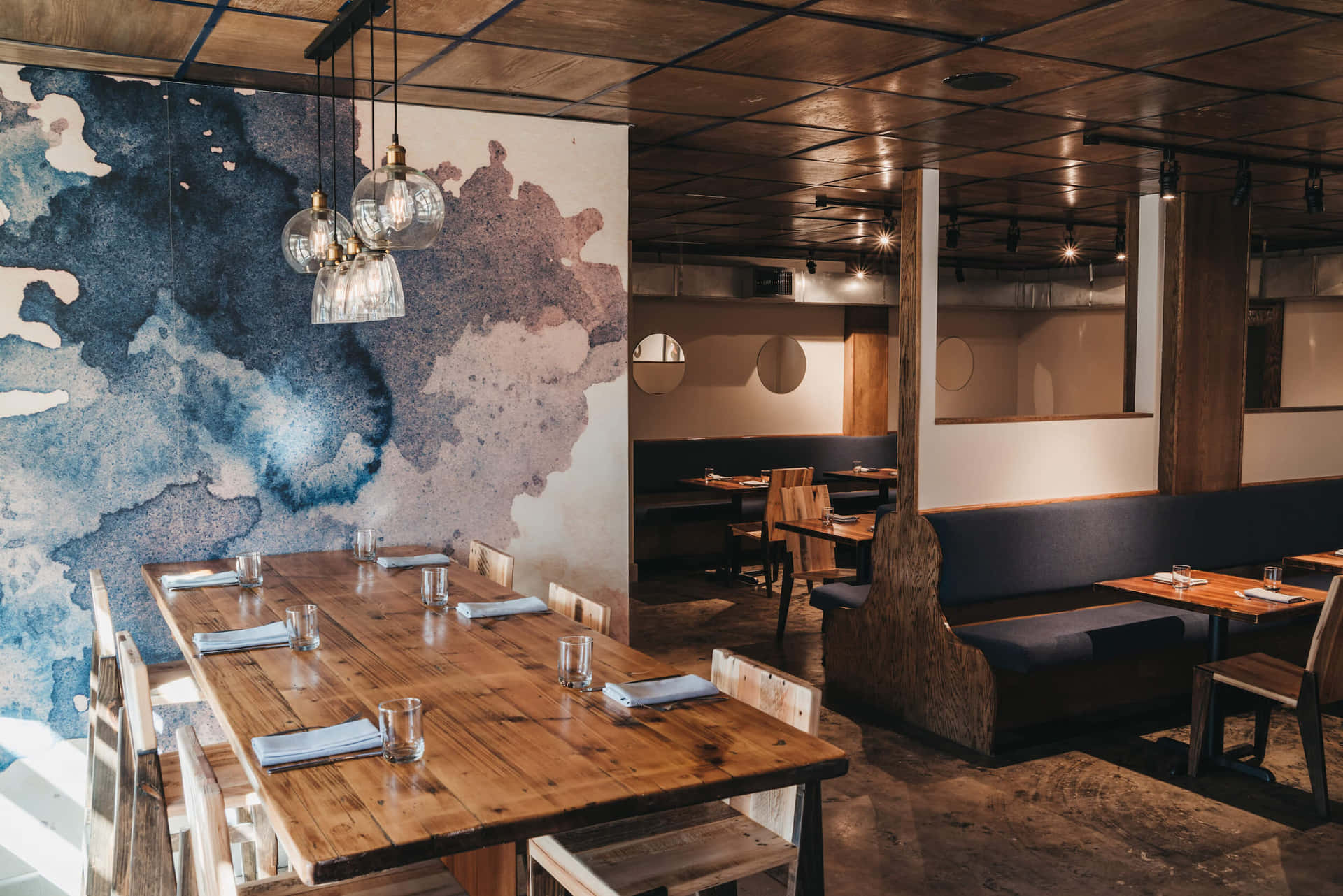 A Restaurant With Wooden Tables And Chairs And A Mural