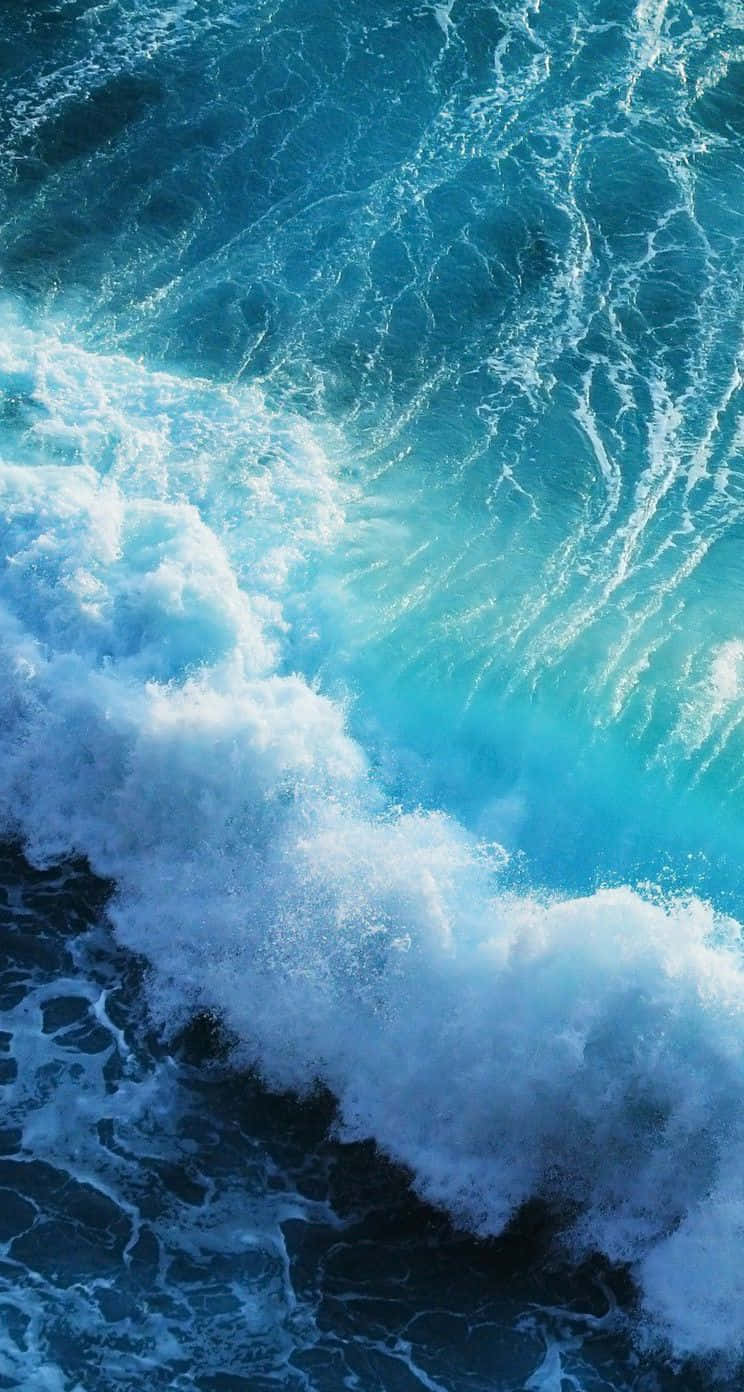 Download A Blue Wave Is Crashing Into The Ocean Wallpaper | Wallpapers.com