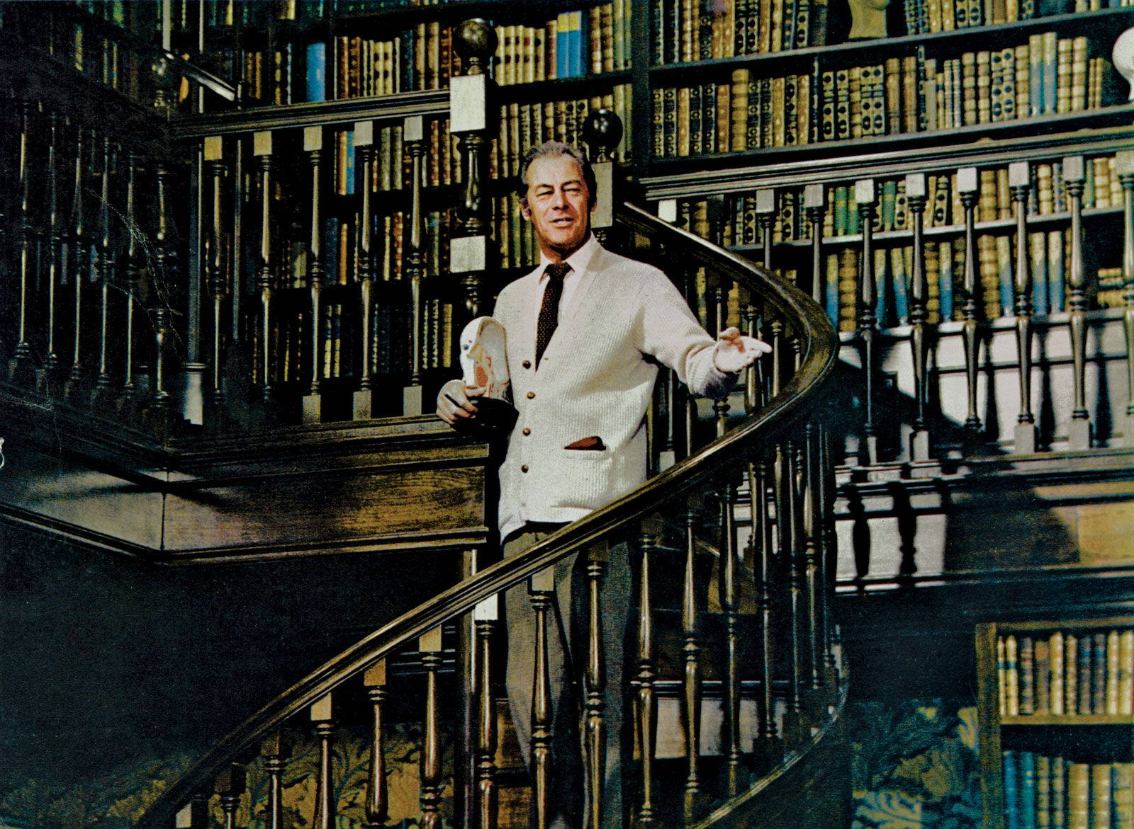 Distinguished actor Rex Harrison walking down the grand library stairs. Wallpaper