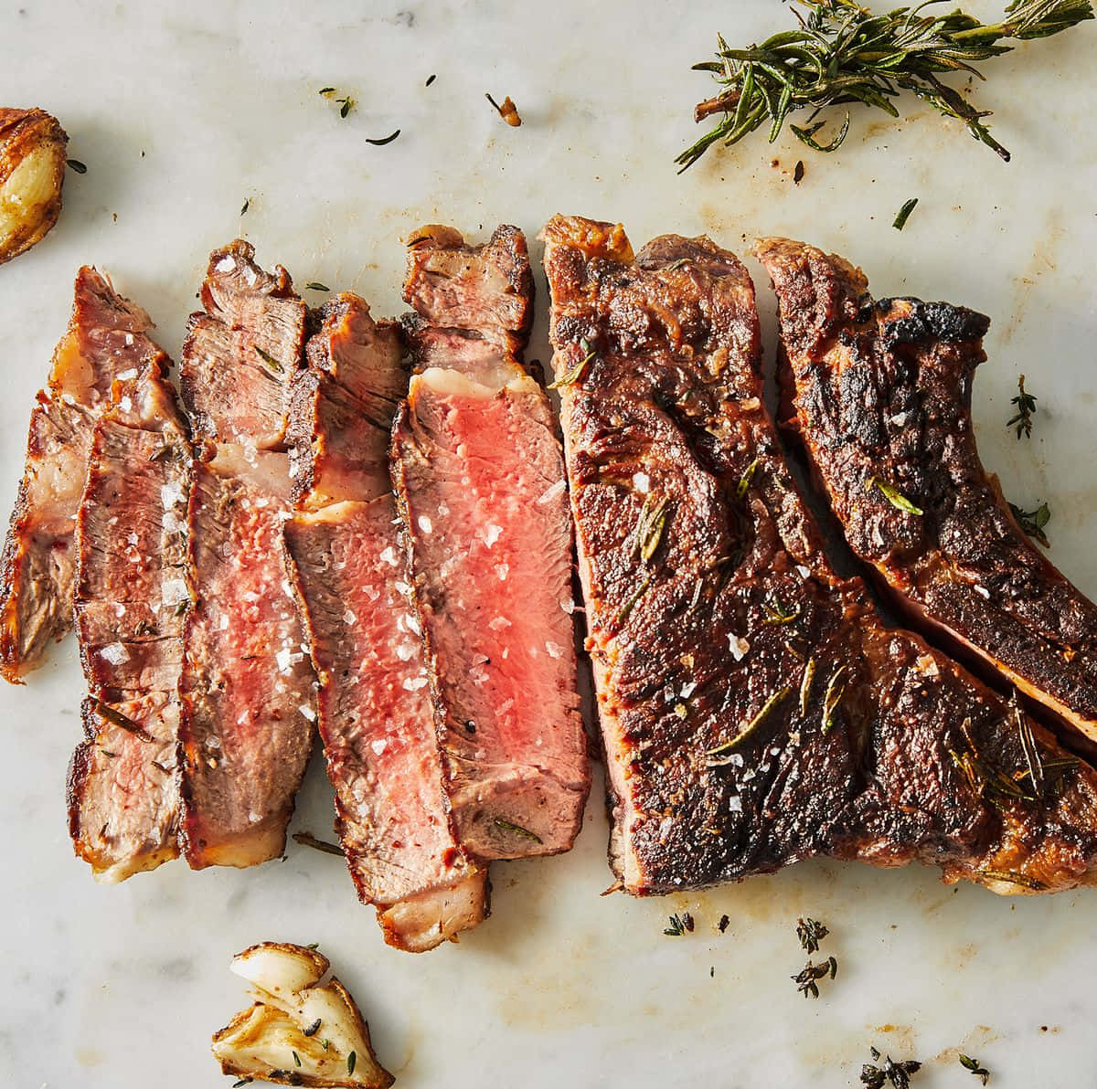 A Steak With Rosemary And Garlic On A Marble Countertop