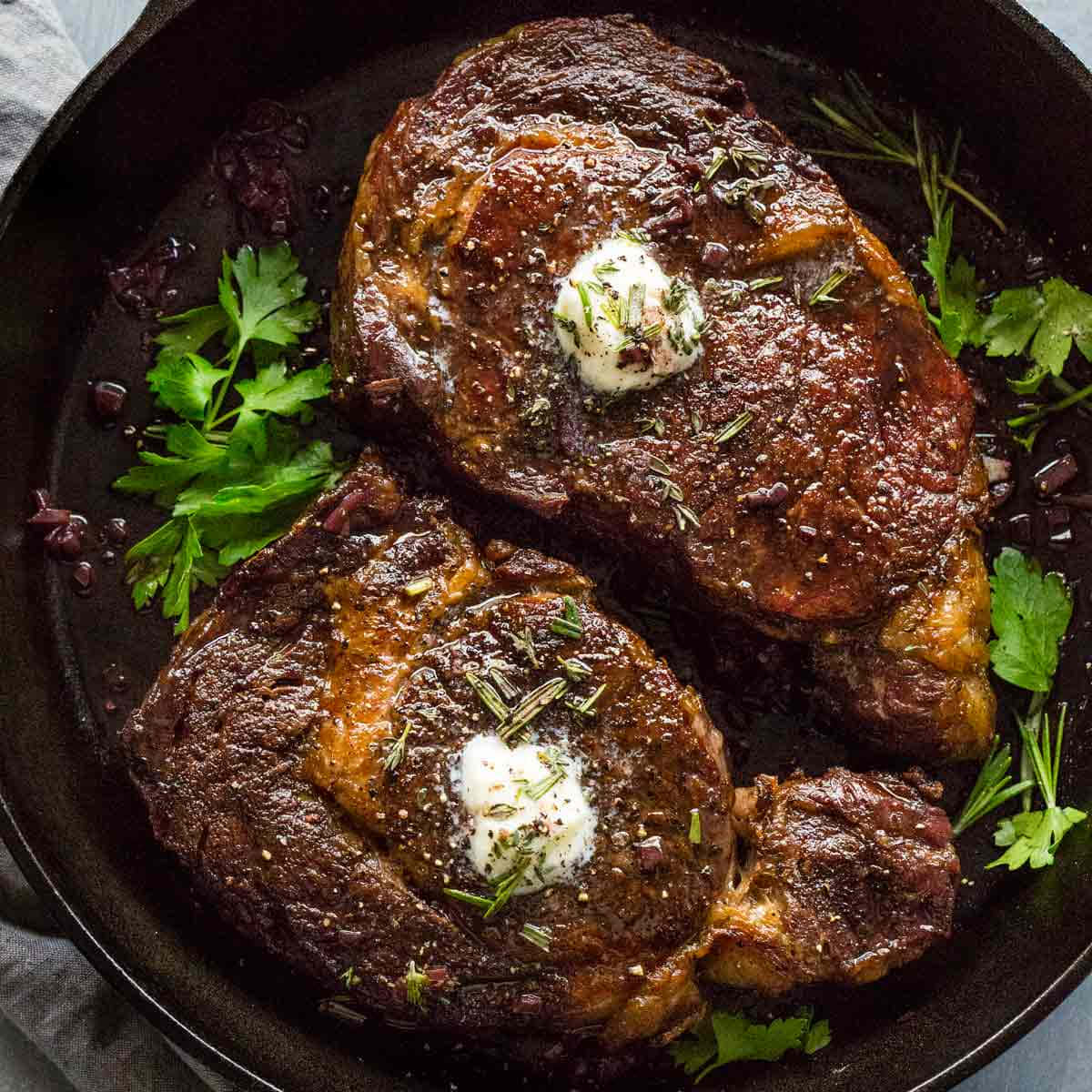 Two Steaks In A Skillet With Herbs And Sour Cream