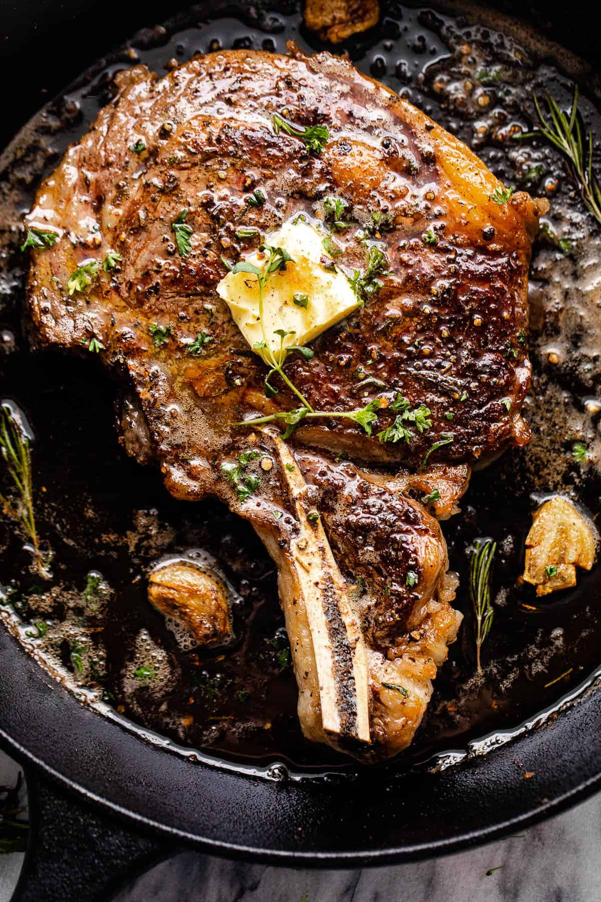 A Steak In A Skillet With Butter And Herbs