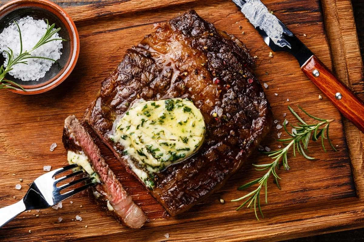 Steak With Butter And Herbs On A Wooden Cutting Board