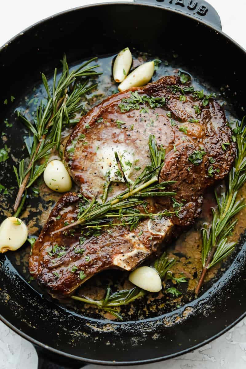 A Steak With Rosemary And Garlic In A Skillet