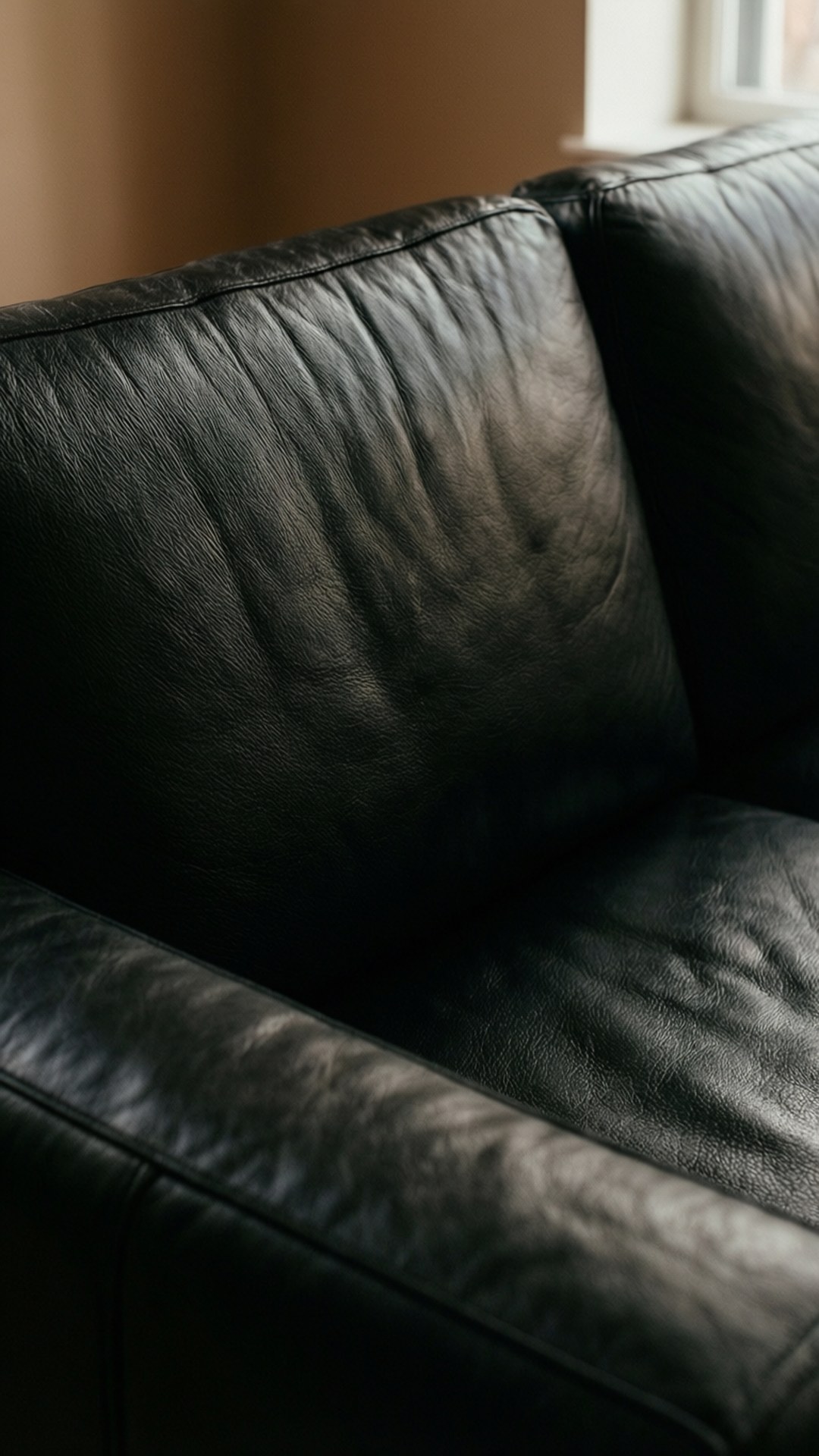 En närbild av en svart lädersoffa som visar detaljerad ådring och sömmar.