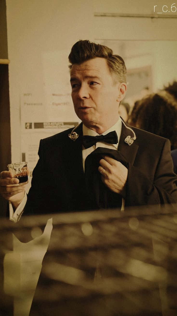 A Man In A Tuxedo Is Holding A Glass
