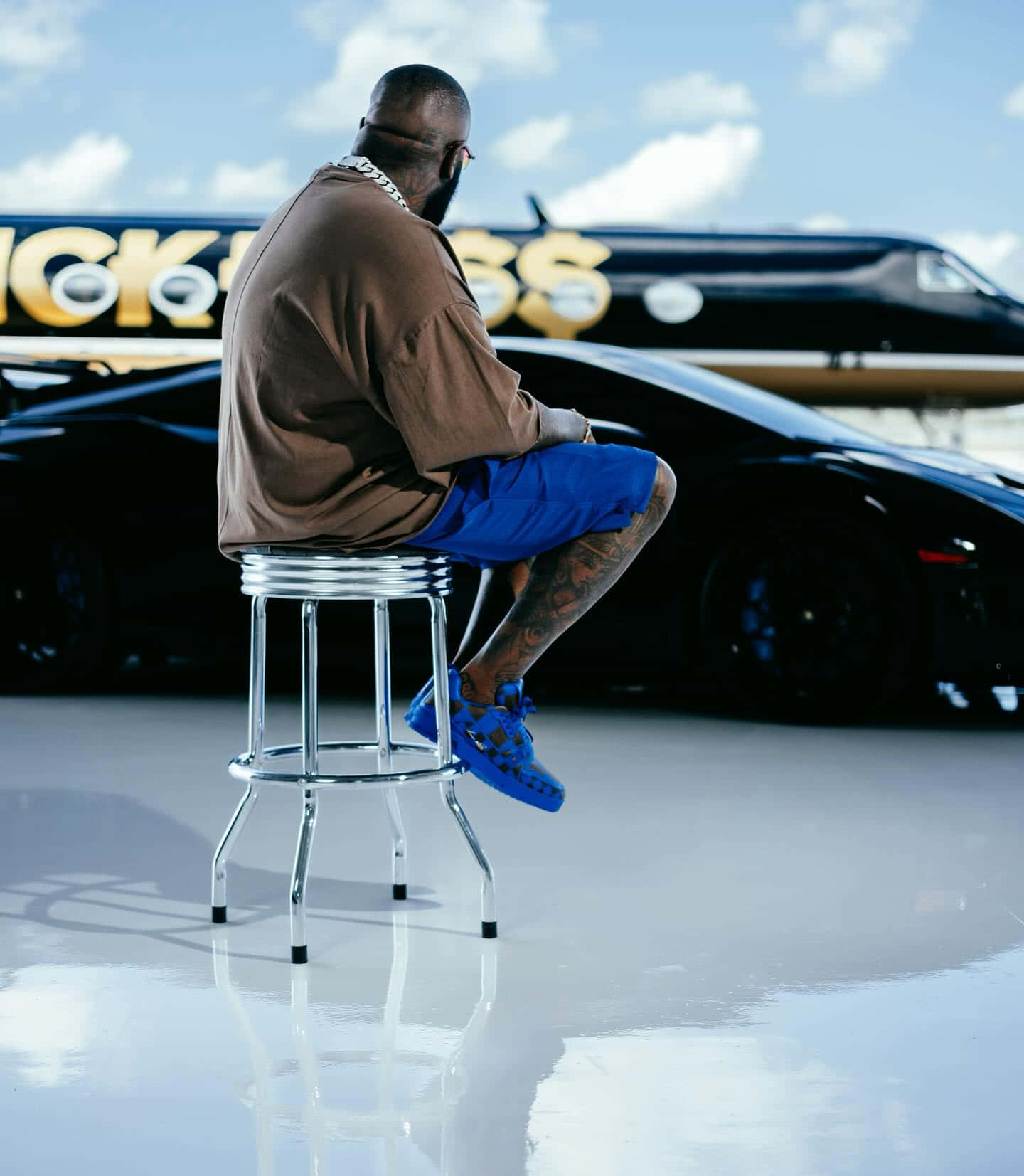 Rick Ross Contemplative Pose With Private Jet Wallpaper
