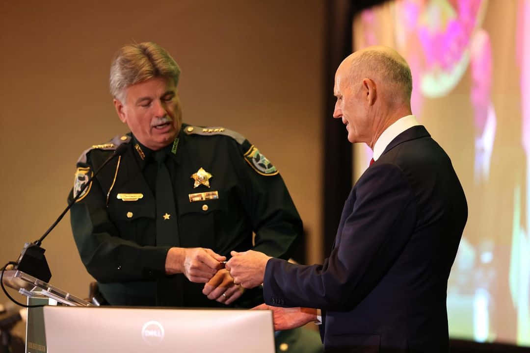 Rick Scott And A Police Officer Wallpaper