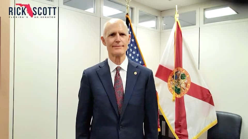 Rick Scott Poses With Flags On Background Wallpaper