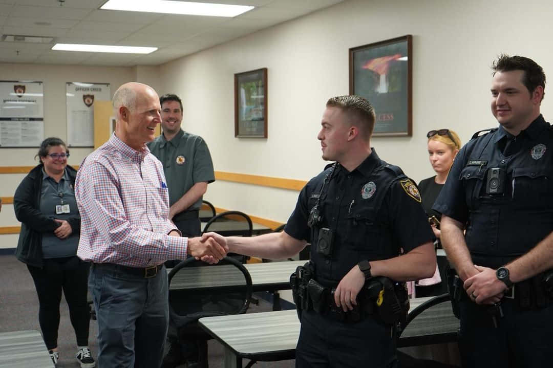 Rick Scott Shaking Hands With Police Officer Wallpaper