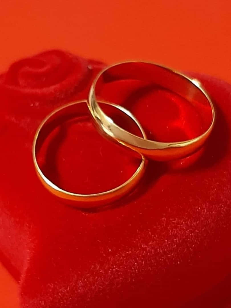 Two Gold Wedding Rings On A Red Velvet