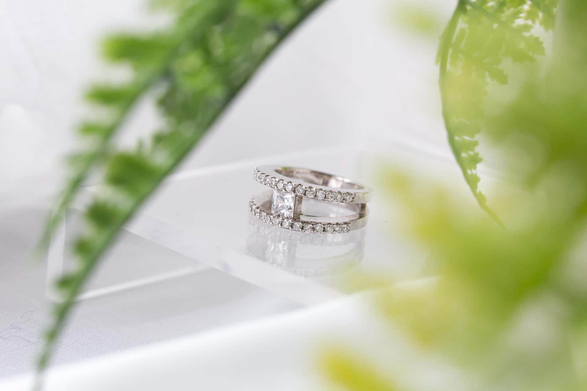 A White Diamond Ring Sitting On A Clear Glass