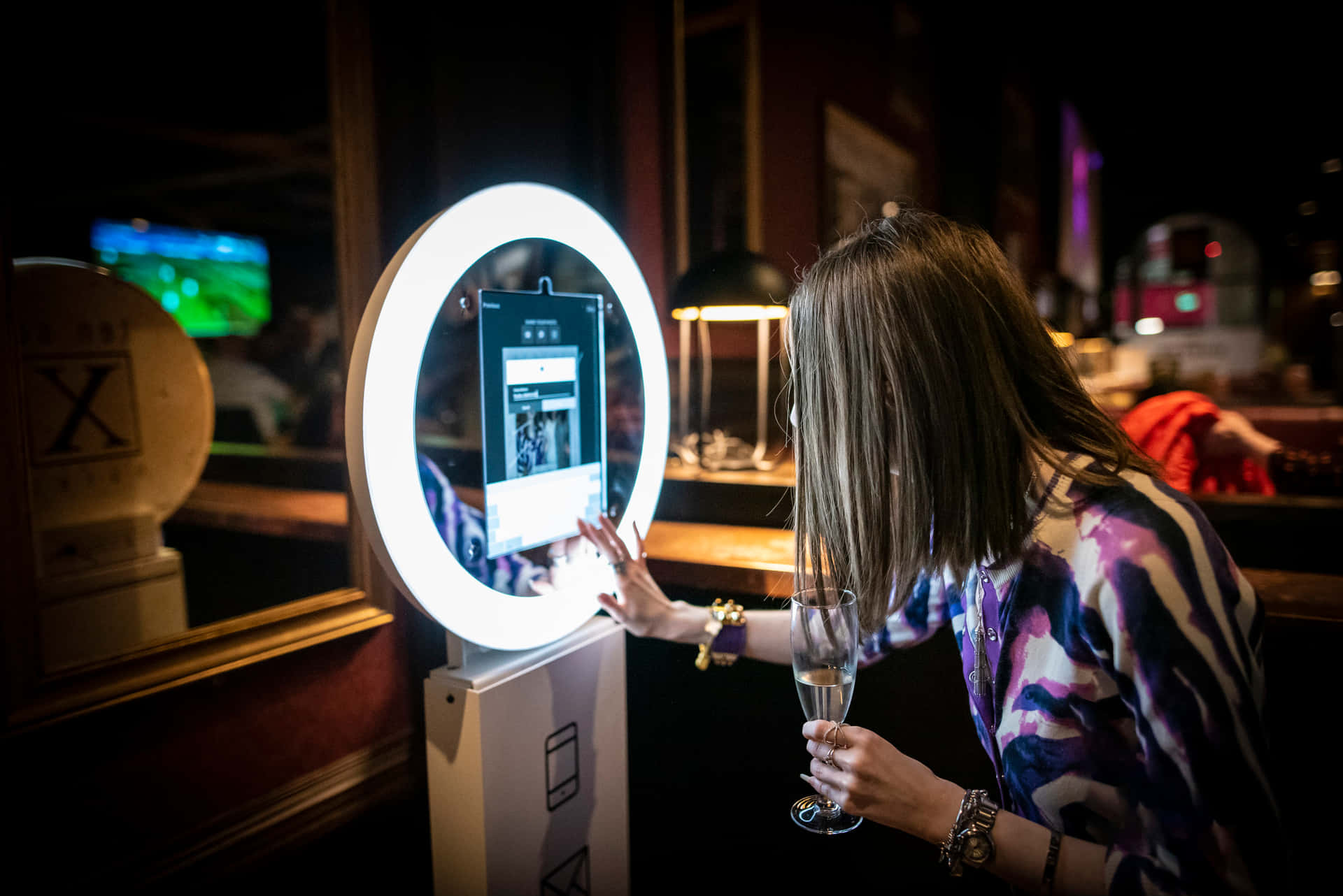 A Woman Is Holding A Glass Of Wine In Front Of A Photo Booth