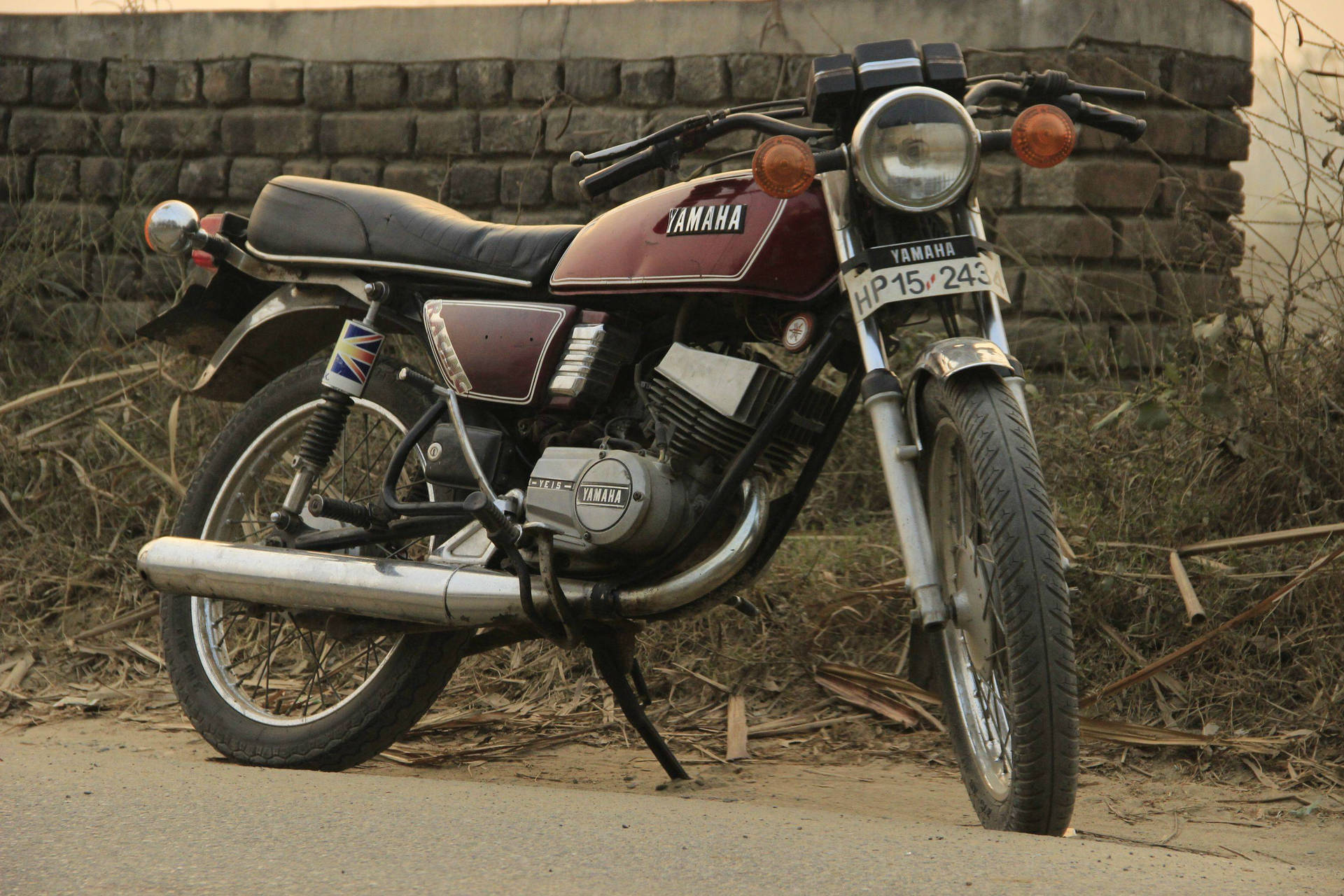 Vägkantensröda Yamaha Rx100-motorcykel. Wallpaper